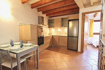 A kitchen with a table and chairs and a stainless steel refrigerator