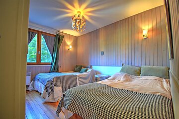A bedroom with two beds and a lamp hanging from the ceiling