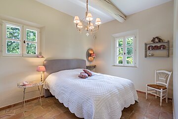 A bedroom with a bed a chair and a chandelier
