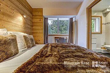 A bedroom with a fur blanket and a sign that says mountain base immobilier real estate