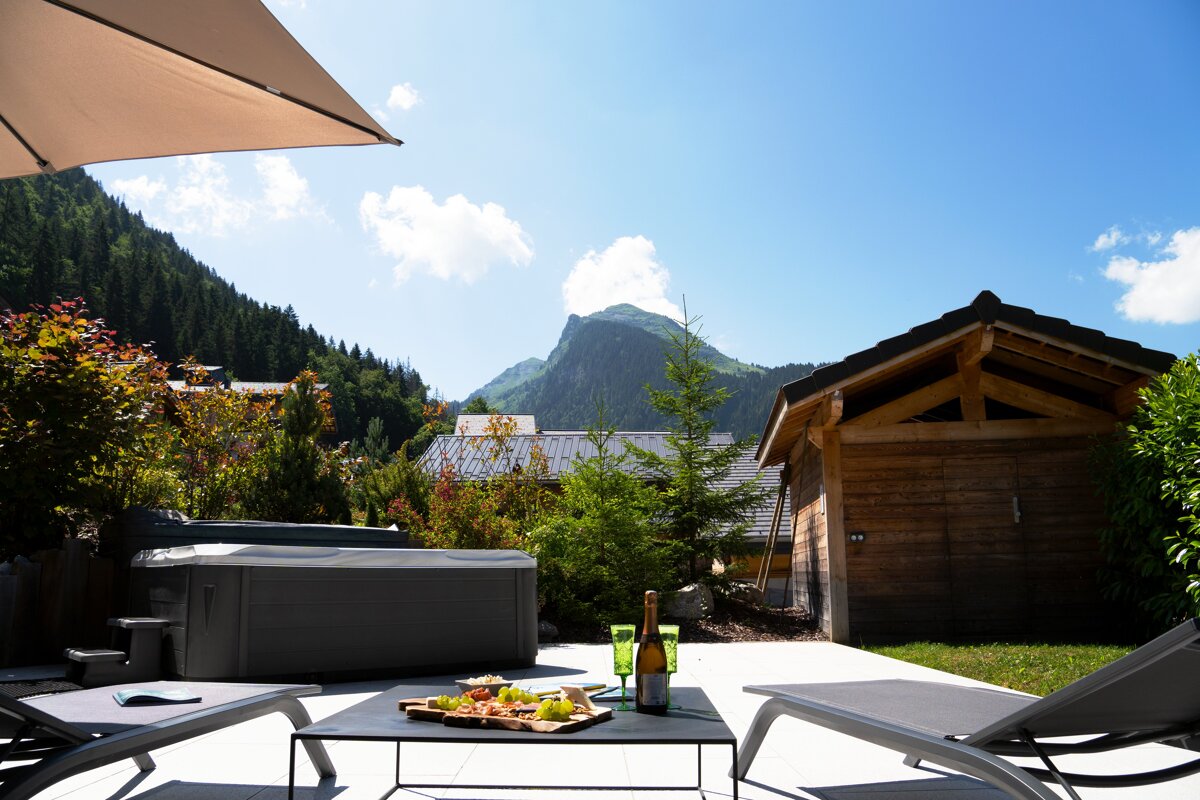 A bottle of wine sits on a table in front of a hot tub
