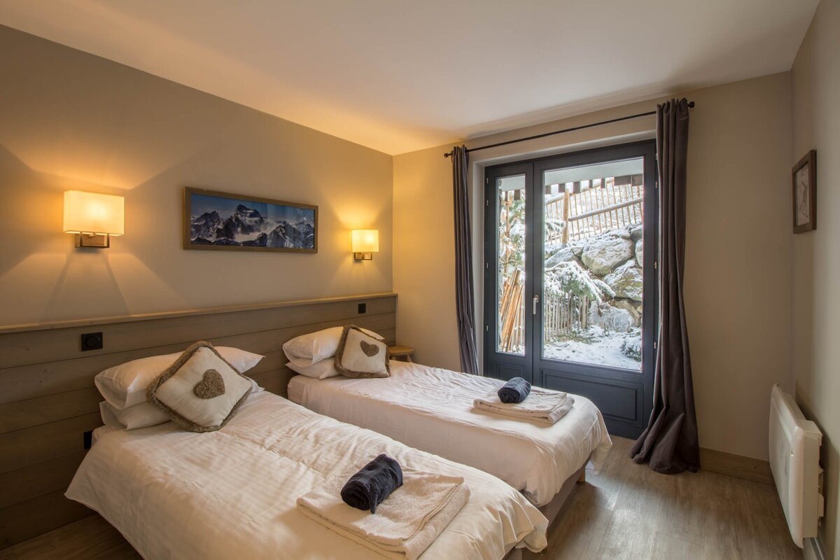 A bedroom with two beds and a picture of mountains on the wall