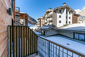 A balcony overlooking a snowy mountain with a building in the background
