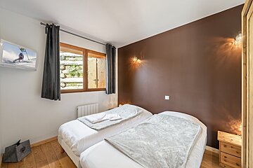 A bedroom with two beds and a flat screen tv