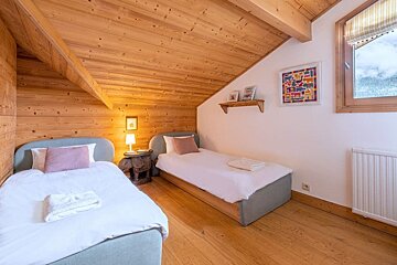 A bedroom with two beds and a painting on the wall