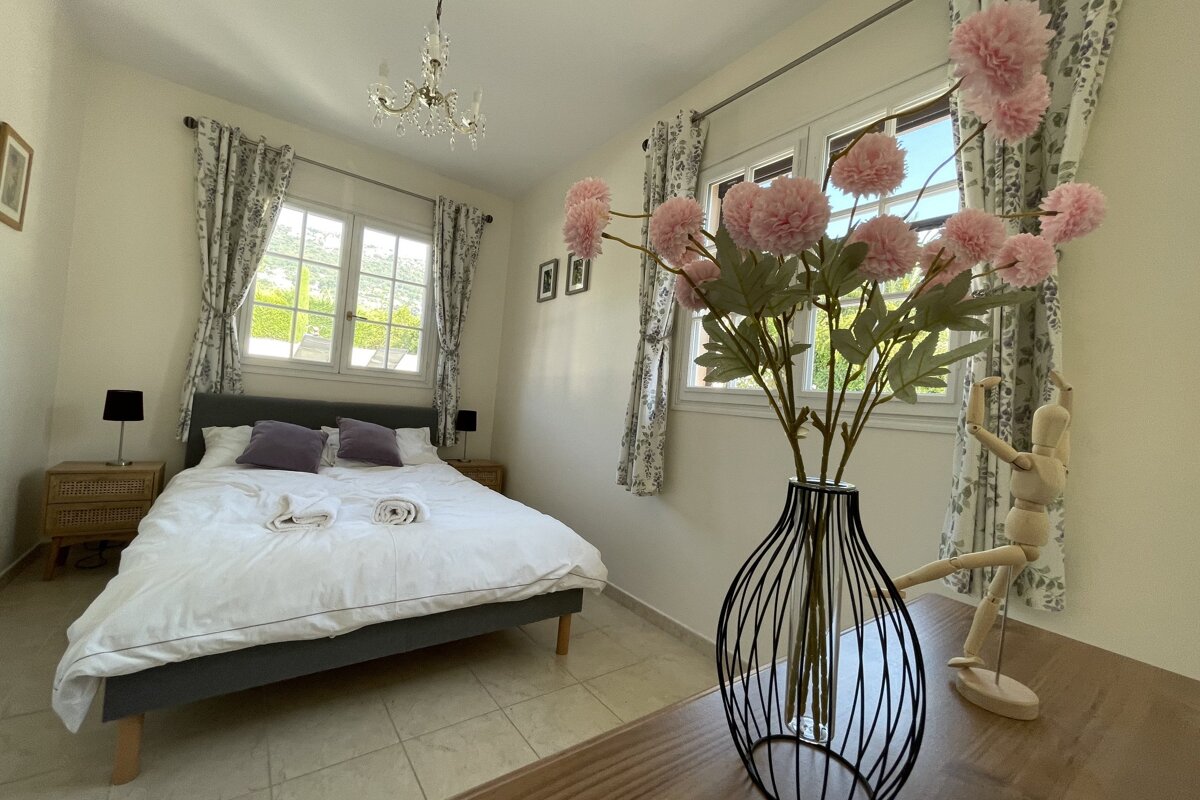 A bedroom with a bed and a vase of flowers