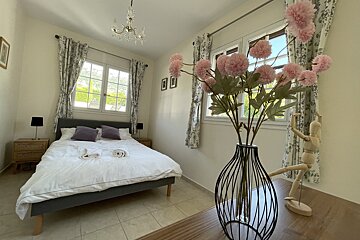 A bedroom with a bed and a vase of flowers