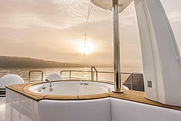 A jacuzzi on a boat with the sun setting in the background