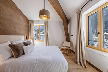 A bedroom with a large bed and a chair