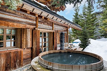 A wooden hot tub sits outside of a wooden cabin