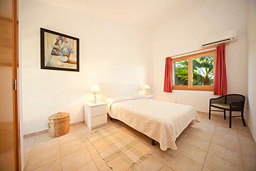 A bedroom with a painting on the wall above the bed