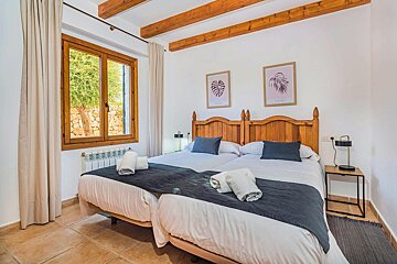 A bedroom with two beds and two paintings on the wall