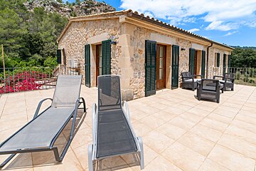 Two lounge chairs are on a patio in front of a stone building
