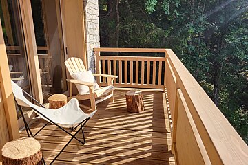 A wooden deck with chairs and stools on it