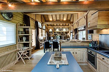 A kitchen in a wooden cabin with a clock on the wall
