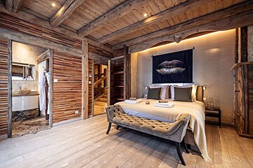 A bedroom with a painting of a woman 's lips on the wall above the bed