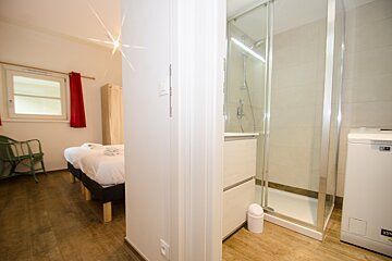 A bathroom with a washing machine and a shower
