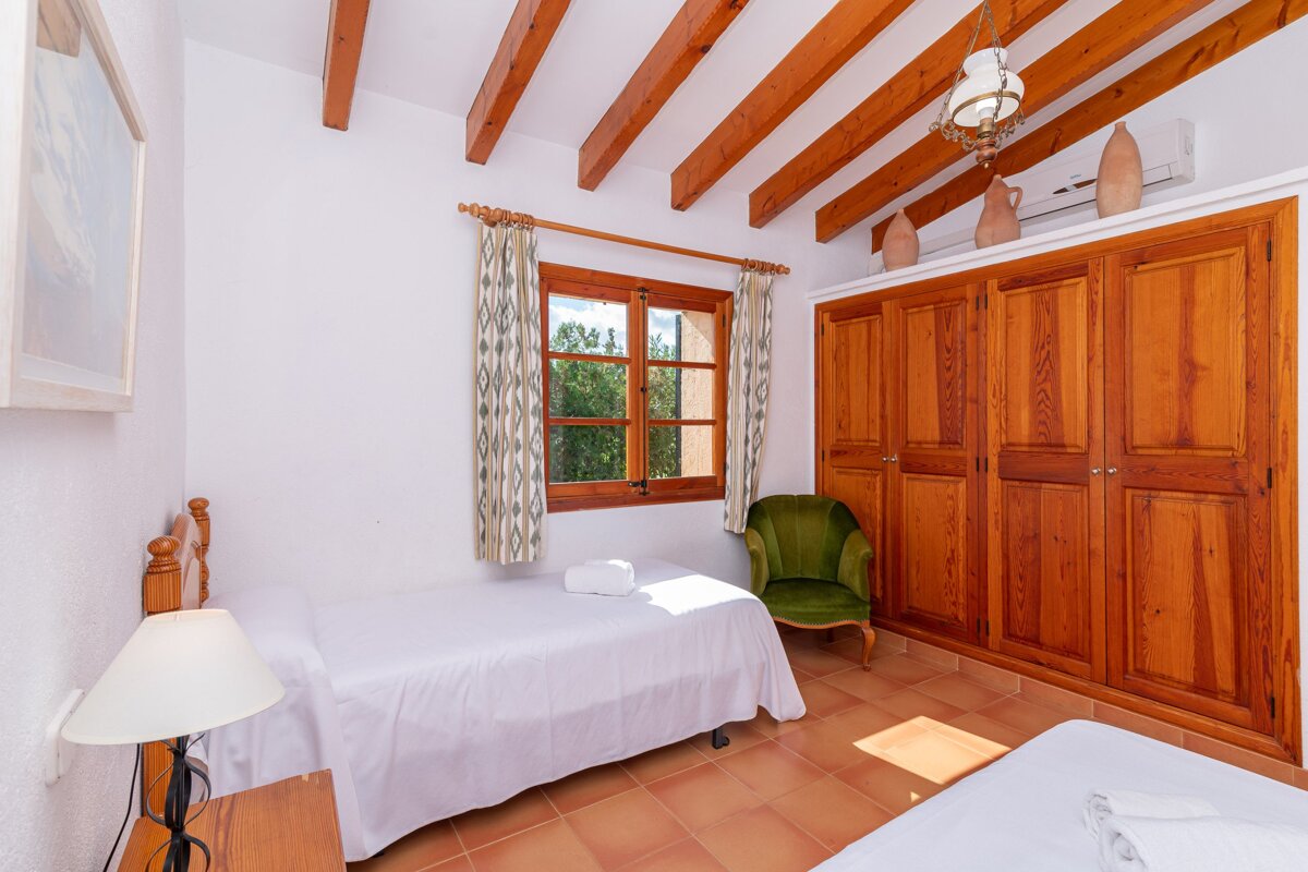 A bedroom with two beds and a green chair