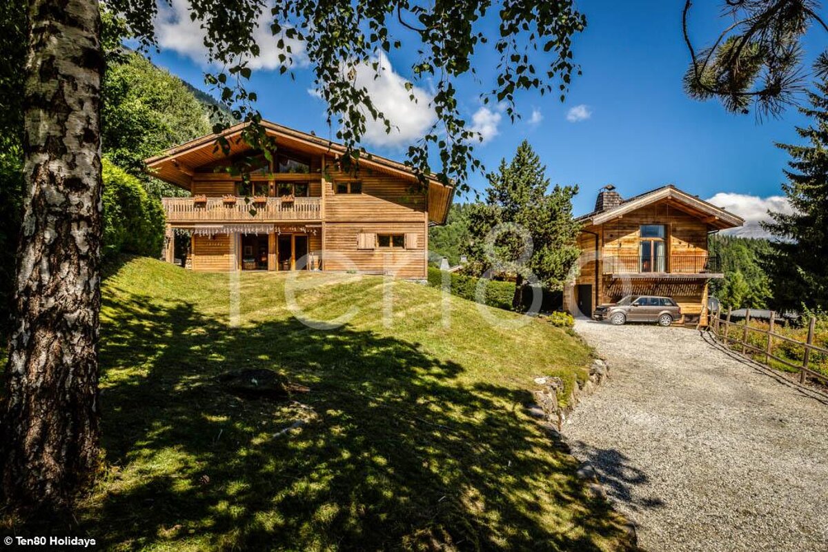 A car is parked in front of a large wooden house