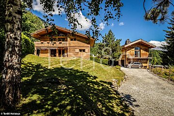 A car is parked in front of a large wooden house