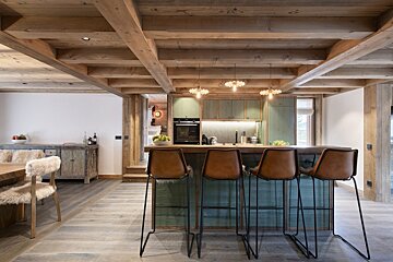 A kitchen with green cabinets and brown leather bar stools