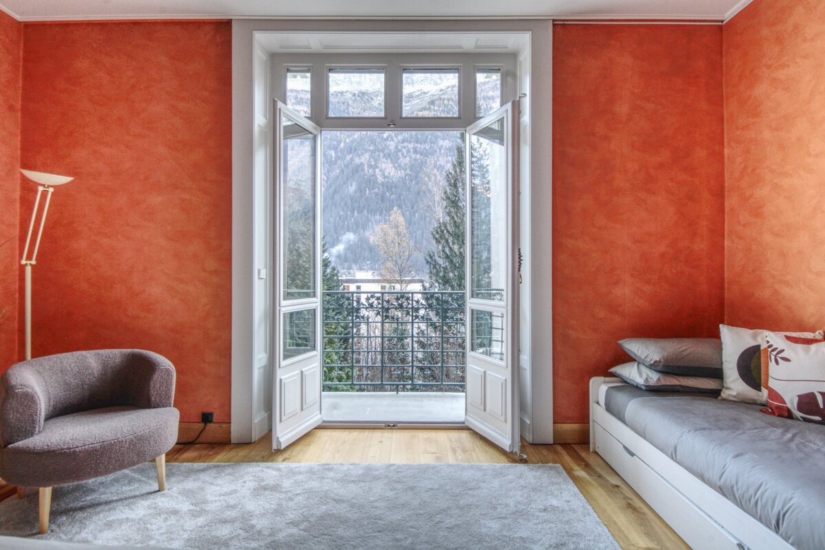 A bedroom with red walls and a view of the mountains