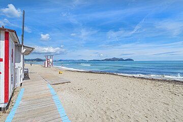 A beach with a wooden walkway leading to the ocean