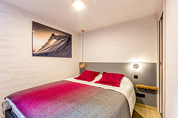 A bedroom with a painting of a mountain on the wall above the bed