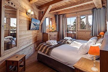 A bedroom with two beds and a television on the wall