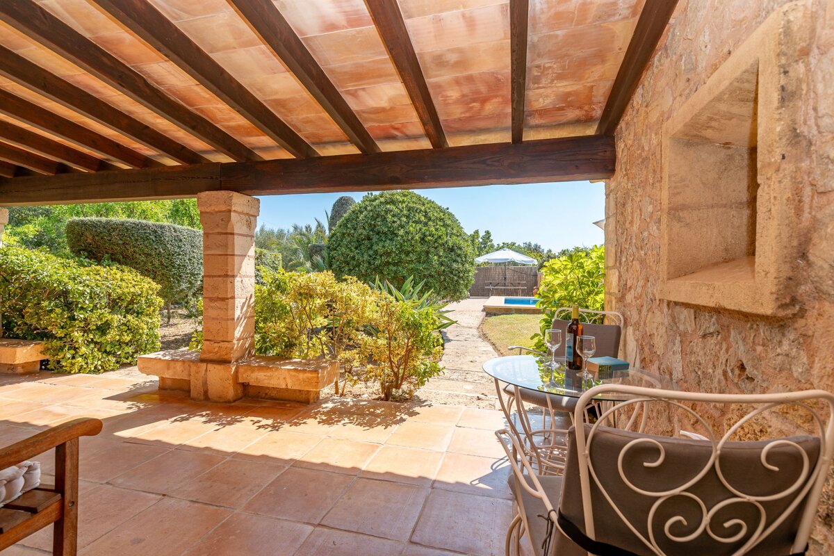 A patio with a table and chairs and a bottle of wine