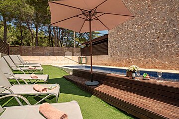 A bottle of wine sits on a wooden deck next to a pool