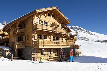 A group of people standing in front of a large wooden house