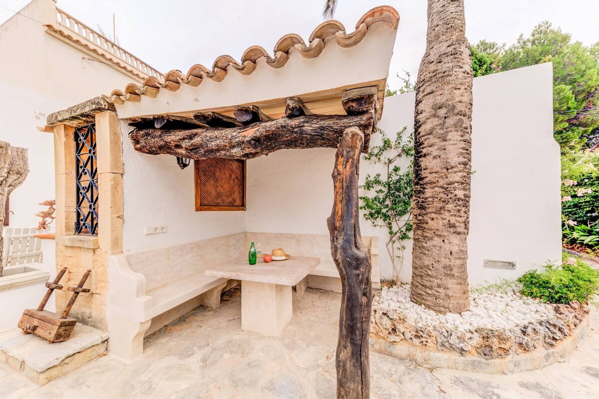 A patio with a table and benches under a wooden pergola