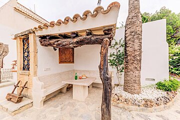 A patio with a table and benches under a wooden pergola