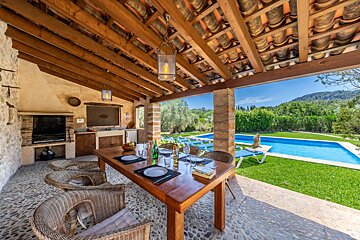A table and chairs under a wooden roof next to a swimming pool