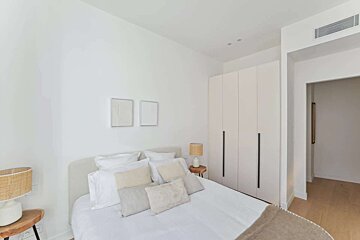 A bedroom with a white bed and two lamps