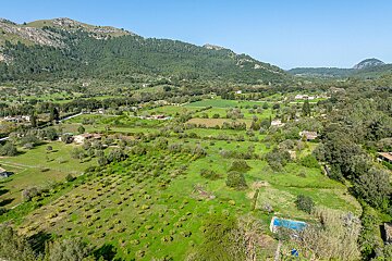An aerial view of a lush green valley with mountains in the background