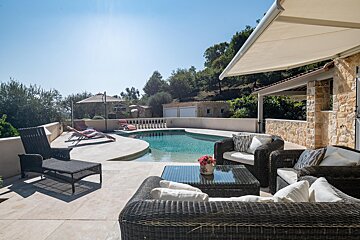 A patio with wicker furniture and a swimming pool