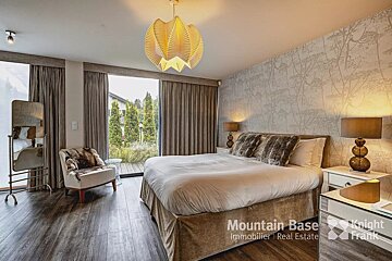 A bedroom with a large bed and a knight frank logo