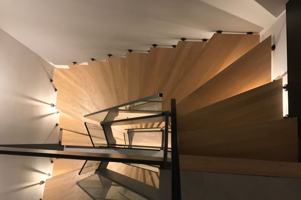 A spiral staircase with wooden steps and a glass railing