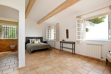A bedroom with a bed and a window with a view of the ocean