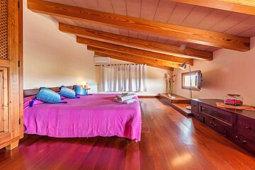 A bedroom with a pink bed and blue pillows