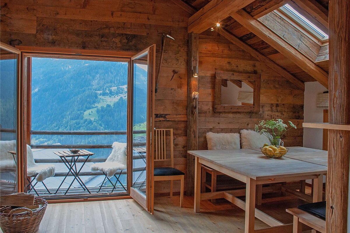 A dining room with a table and chairs and a view of the mountains