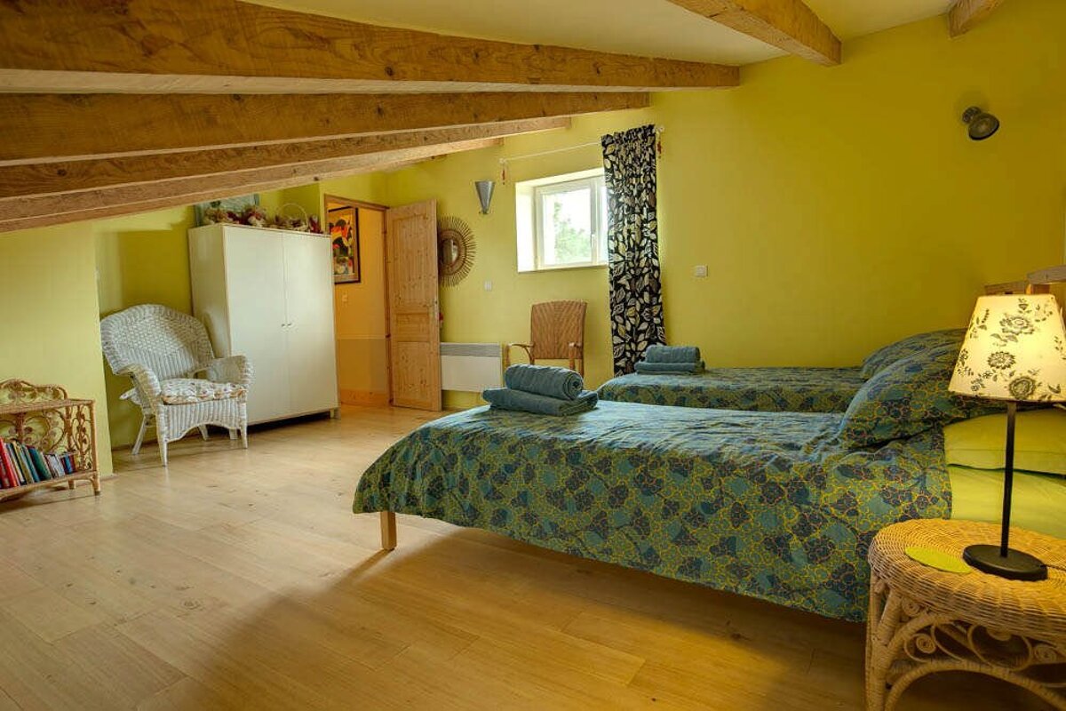 A bedroom with two beds and a wicker chair