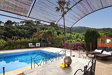A large swimming pool with a table and chairs in front of it