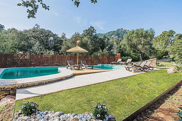 A swimming pool surrounded by chairs and a straw umbrella