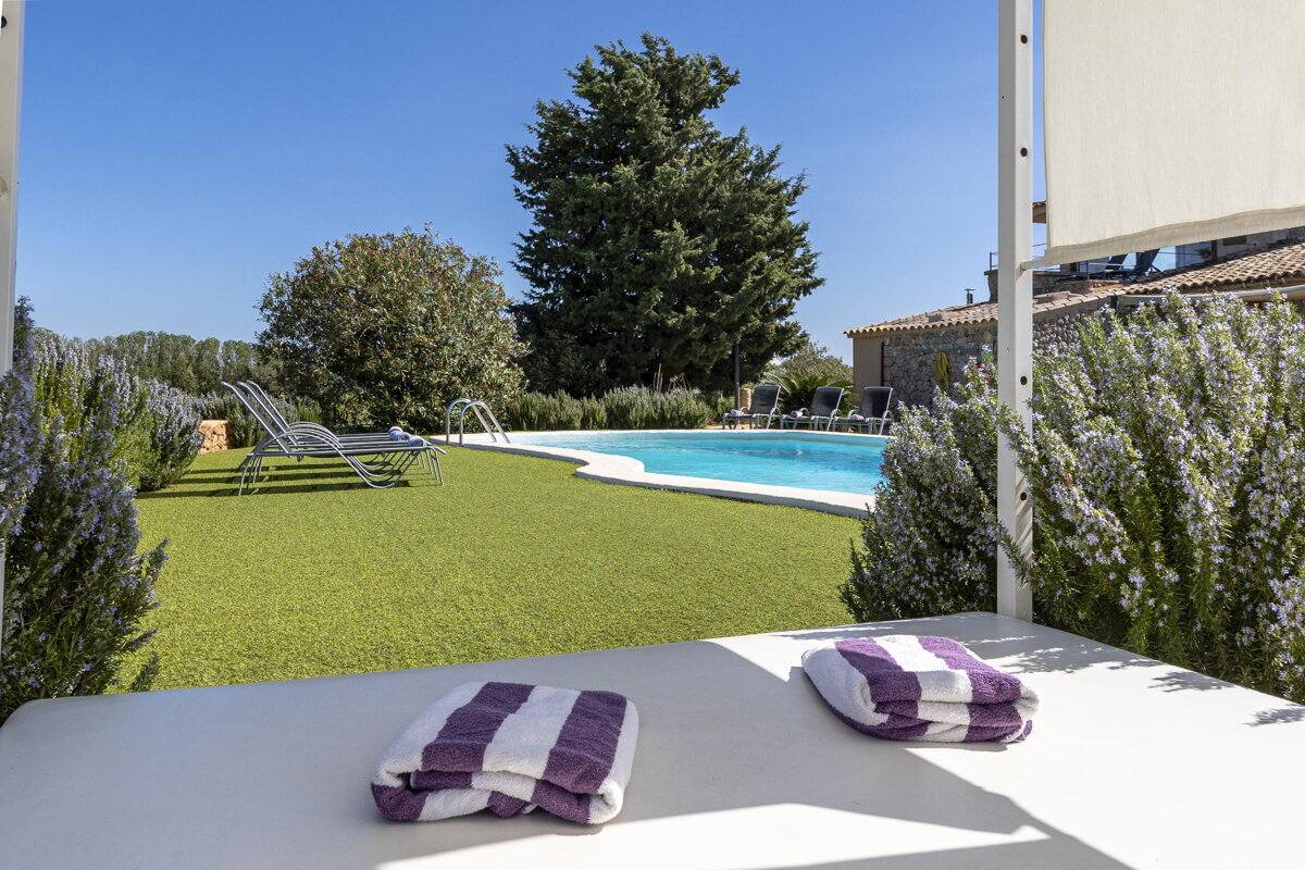 A purple and white striped towel sits on a bed in front of a swimming pool