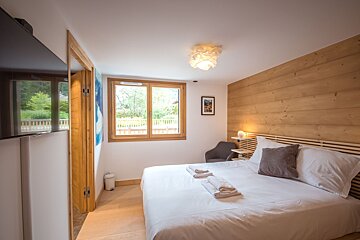 A bedroom with a large bed and a flat screen tv