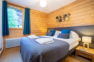 A bedroom with a large bed and blue curtains