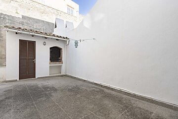A white building with a brown door and shutters
